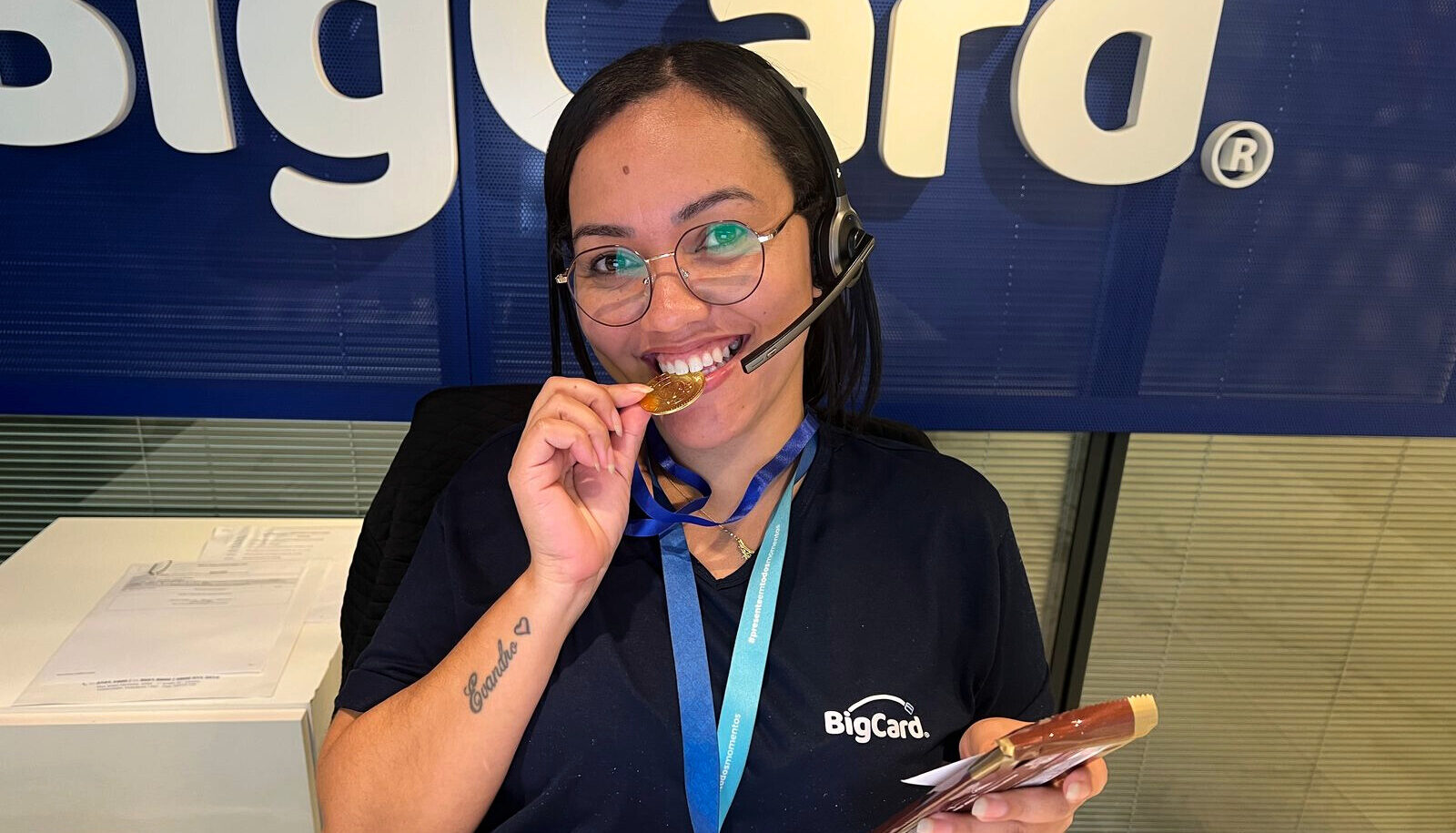 Colaboradora da BigCard sorrindo com medalha e prêmio após vencer desafio da EcoGames.